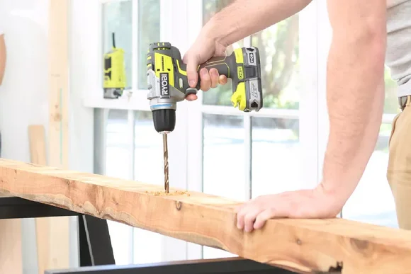 Person bohrt mit einem Akkuschrauber in ein Holzbrett.